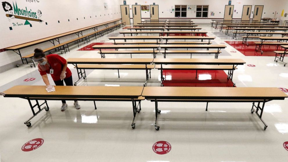 PHOTO: A Garland Independent School District custodian wipes down tables in the cafeteria at Stephens Elementary School in Rowlett, Texas, Wednesday, July 22, 2020.
