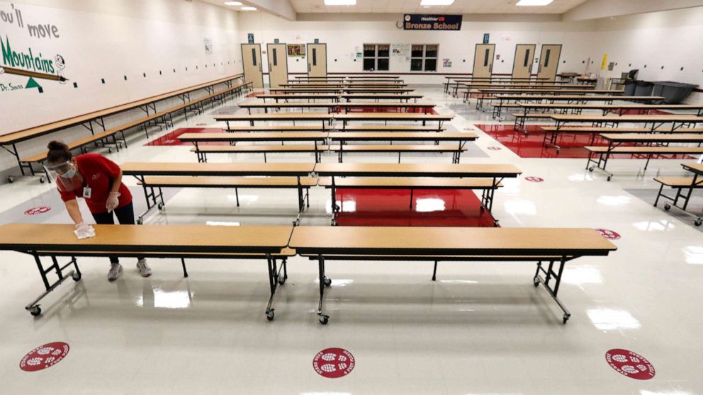 PHOTO: A Garland Independent School District custodian wipes down tables in the cafeteria at Stephens Elementary School in Rowlett, Texas, Wednesday, July 22, 2020.