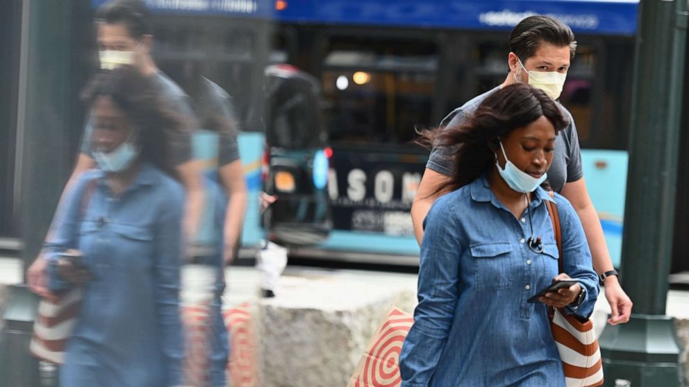 PHOTO: (FILES) In this file photo people wearing facemasks carry shopping bags as they walk on a street near Herald Square on June 25, 2020 in New York City.