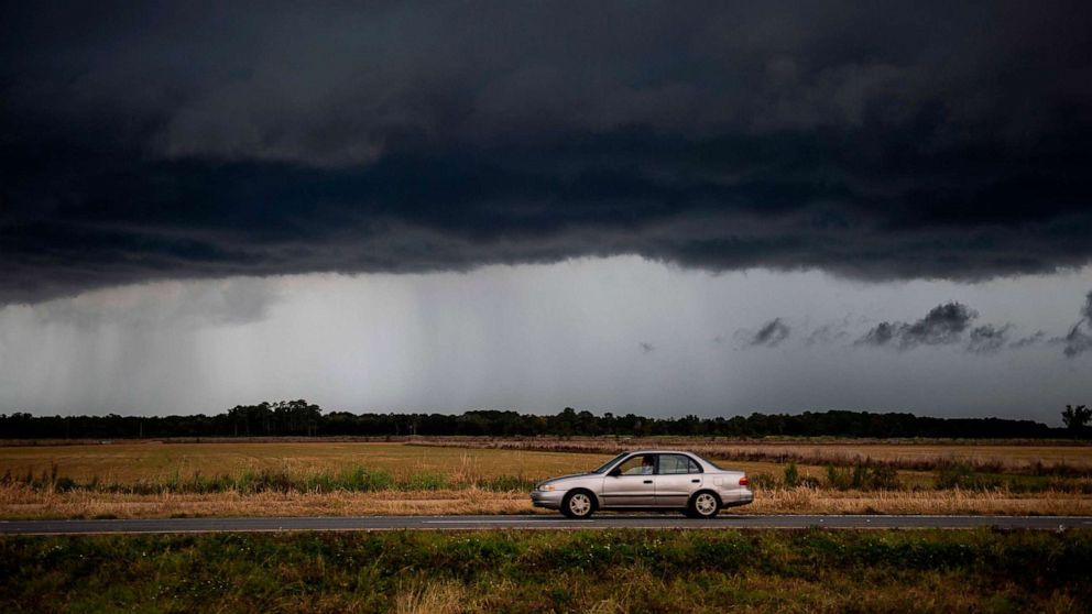 PHOTO: A car drives under an ominous rain cloud from tropical storm Marco as locals prepare for the arrival of hurricane Laura near Lake Charles, Louisiana on August 25, 2020. 