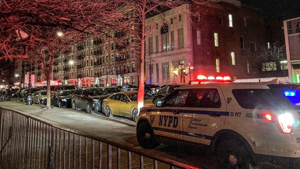 Police secure the scene outside a six story residential building, left, where two NYPD officers where shot responding to a domestic disturbance call in Harlem, Friday Jan. 21, 2022, in New York. (AP Photo/Jennifer Peltz)