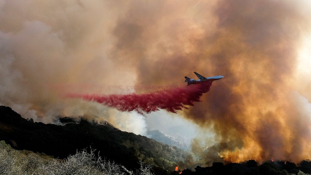 An air tanker drops retardant on a wildfire Wednesday, Oct. 13, 2021, in Goleta, Calif. A wildfire raging through Southern California coastal mountains threatened ranches and rural homes and kept a major highway shut down Wednesday as the fire-scarre