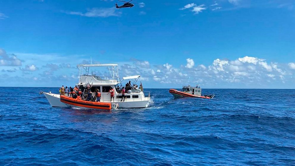 This image provided by the U.S. Coast Guard shows Coast Guard law enforcement crews aiding people from an unsafe and overloaded 40-foot cabin cruiser about 20 miles off Boca Raton, Fla., Oct. 12, 2022. The people were transferred to Bahamian authorit