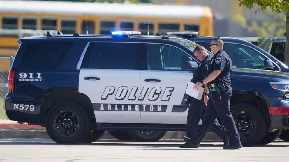 FILE - In this Wednesday, Oct. 6, 2021, file photo, law enforcement officers walk in the parking lot of Timberview High School after a shooting inside the school located in south Arlington, Texas. A 15-year-old injured in the Timberview High School s