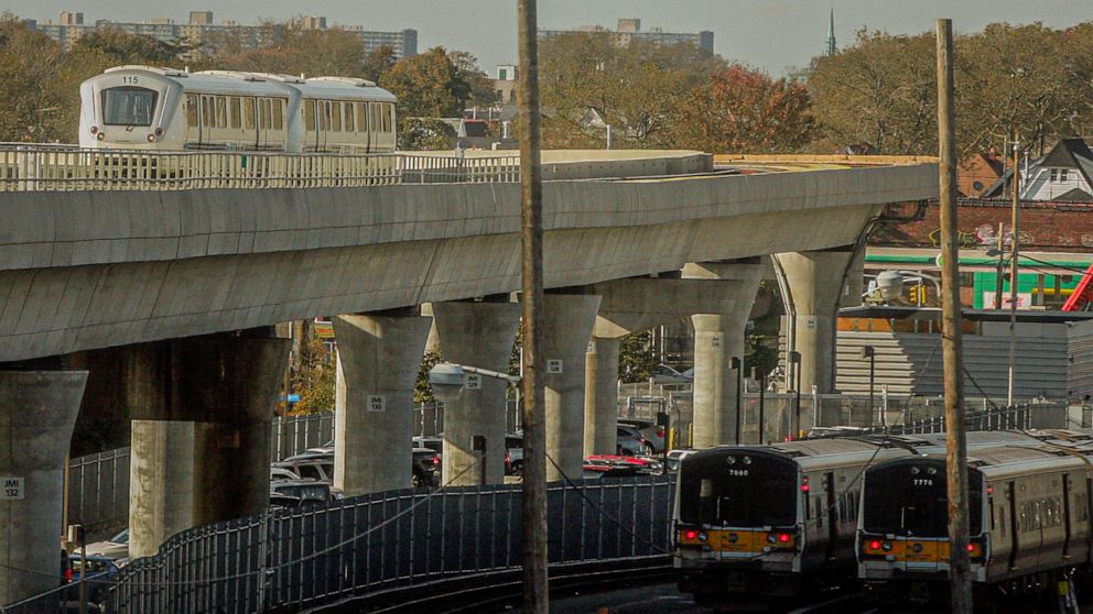 FILE - This Thursday, Nov. 1, 2012, file photo shows the JFK airport Airtrain, left, on overhead tracks above Long Island Rail Road trains near Jamaica Station in Queens, N.Y. Plans to build a similar rail link connecting New York City to LaGuardia A