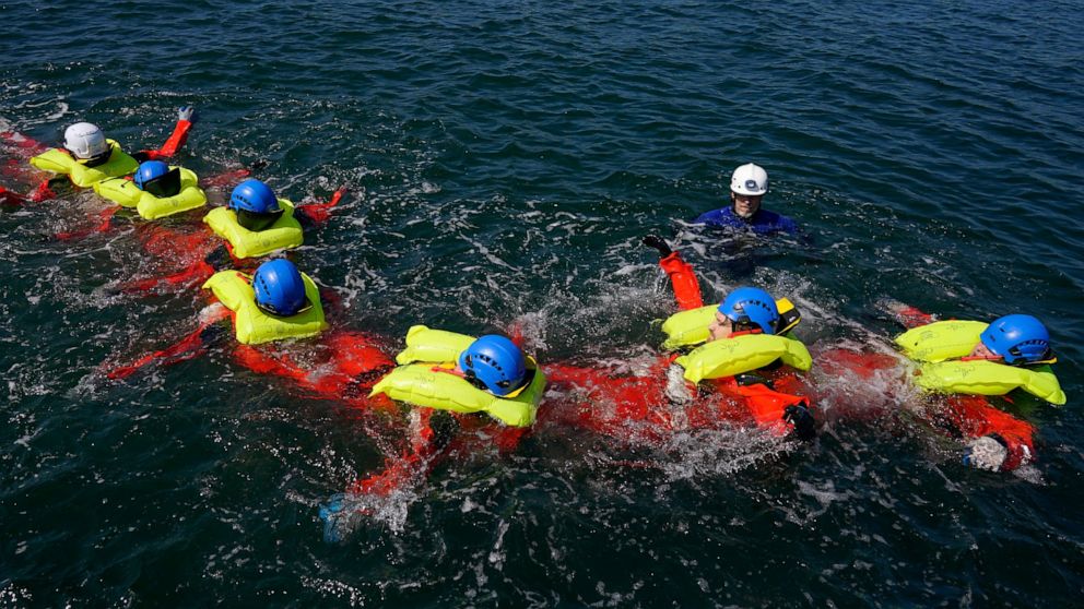 Participants in a Global Wind Organisation certification class learn how to do a group survival float at the Massachusetts Maritime Academy in Bourne, Mass., Thursday, Aug. 4, 2022. At the 131-year-old maritime academy along Buzzards Bay, people who 