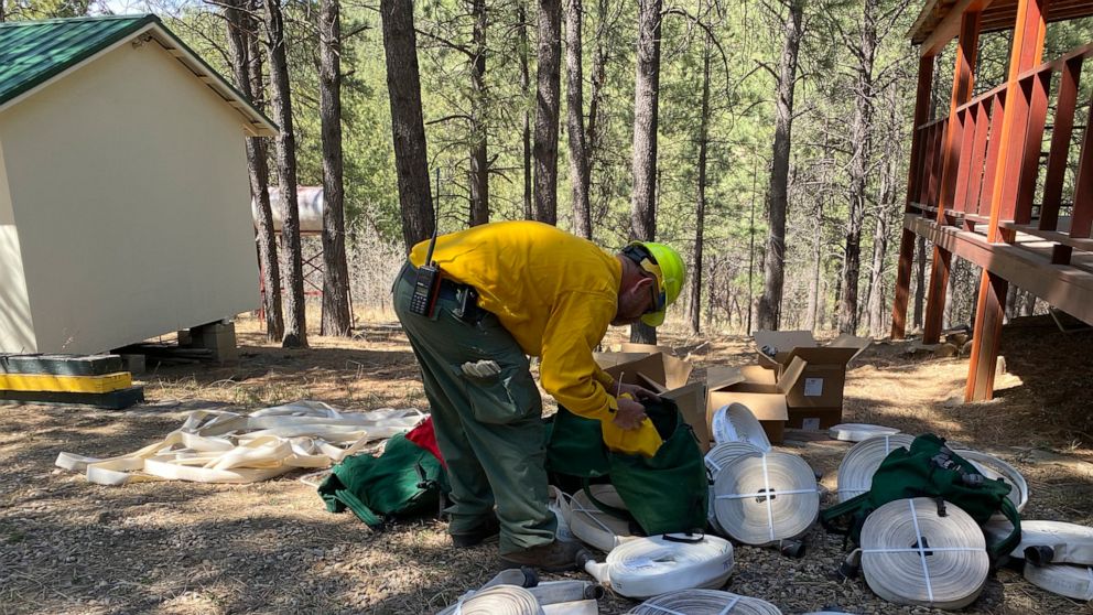 In this photo released by the U.S. Forest Service, a firefighter gathers hose and fittings to assemble sprinkler protection systems in the Santa Fe National Forest in New Mexico on Thursday, April 28, 2022. Thousands of firefighters continued to slow