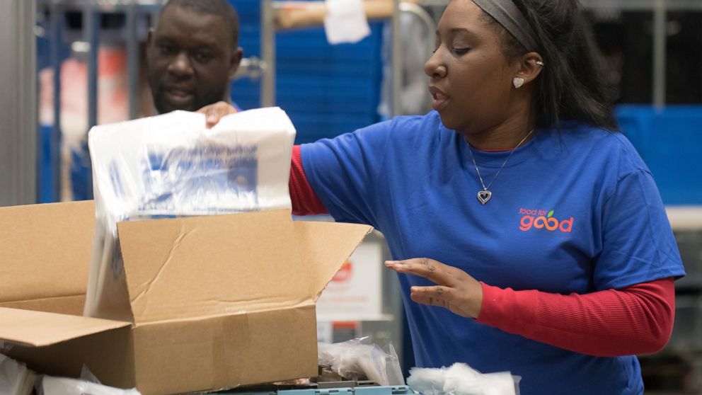 In this 2018 photo provided by Holt Haynsworth, Portia Thomas packs boxes at the Food For Good Warehouse in Austin, Texas in 2018. At the start of the pandemic, the need for the food Jaron Barganier’s nonprofit, Be a Champion, provides to kids throug