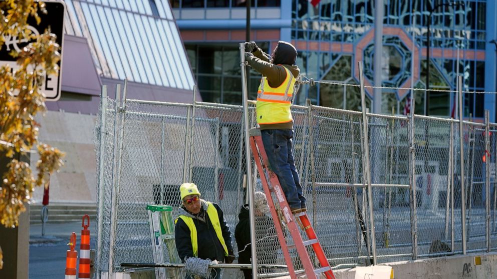 FILE - In this Wednesday, Feb. 23, 2021 file photo, Workers install barbed wire on fencing outside the Hennepin County Government Center in Minneapolis, as part of security preparation for the trial of former Minneapolis police officer Derek Chauvin.