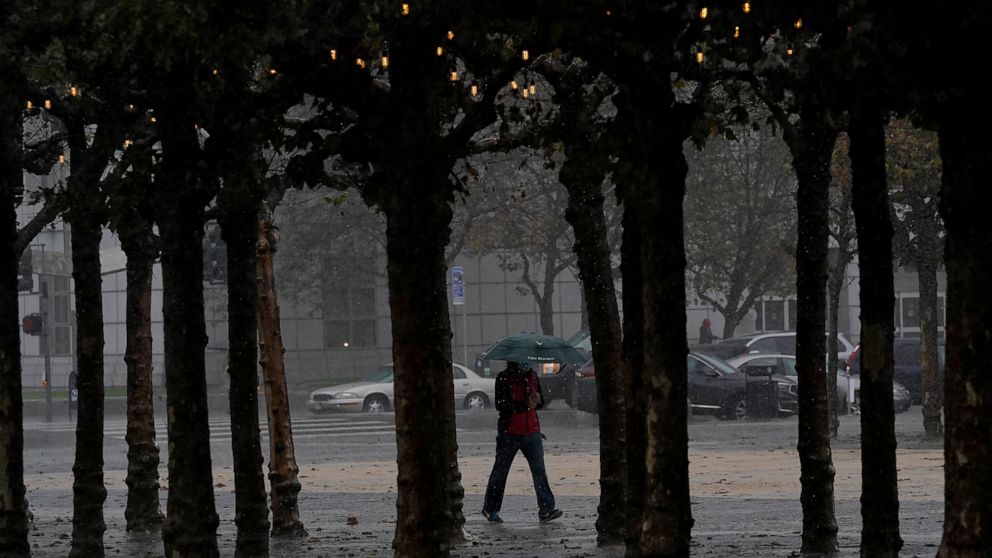 A pedestrian carries an umbrella while walking at Civic Center Plaza in San Francisco, Tuesday, Nov. 8, 2022. A major winter storm pounded California on Tuesday, bringing rain and snow to the drought-stricken state along with possible flash flooding 