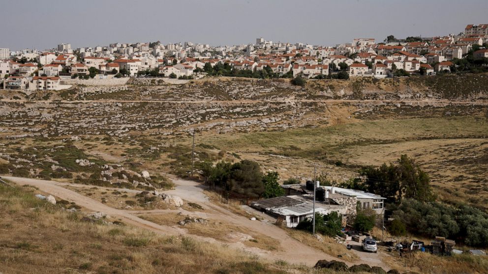 FILE - A Palestinian home sits in a valley, next to the east Jerusalem Jewish Israeli settlement of Pisgat Ze'ev, May 12, 2022. Investigators commissioned by the U.N.-backed Human Rights Council said Tuesday, June 7, 2022, that tensions between Pales