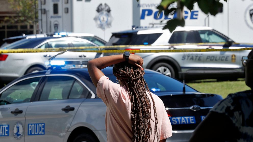 A woman watches as Newport News police officers and Virginia state troopers respond to the scene of a shooting at Heritage High School in Newport News, Va., Monday, Sept. 20, 2021. (Jonathon Gruenke/The Virginian-Pilot via AP)