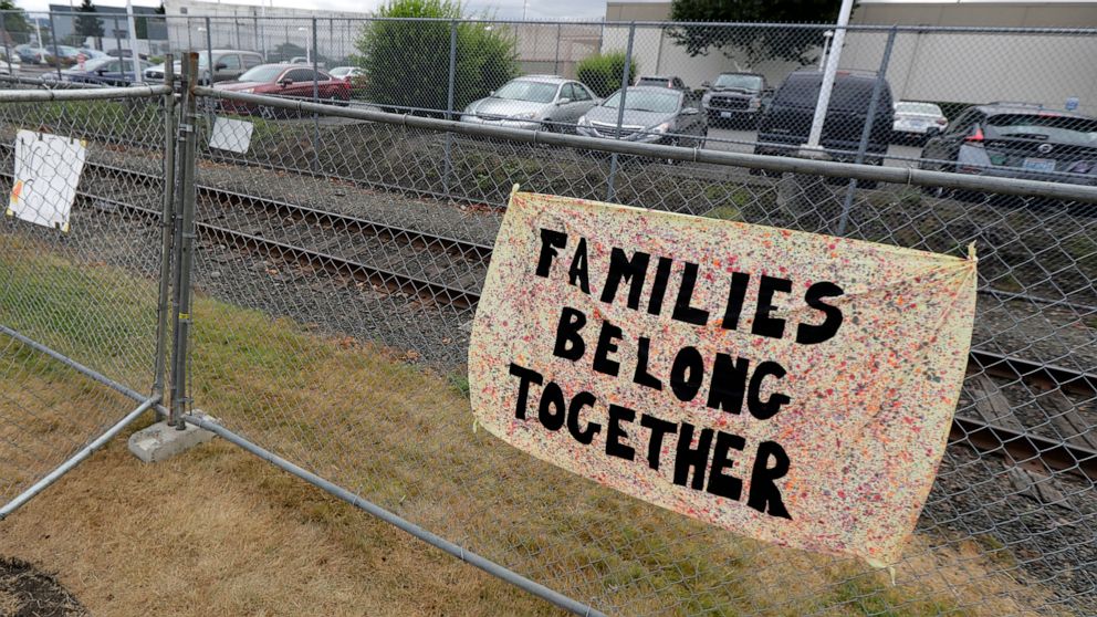 FILE - This July 10, 2018 file photo shows a sign that reads "Families Belong Together" on a fence outside the Northwest Detention Center in Tacoma, Wash. Immigrant rights groups want U.S. Immigration and Customs Enforcement to release detainees at i