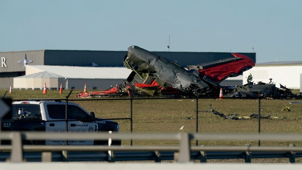 An emergency vehicle sits near debris from two planes that crashed during an airshow at Dallas Executive Airport, Saturday, Nov. 12, 2022. (AP Photo/LM Otero)