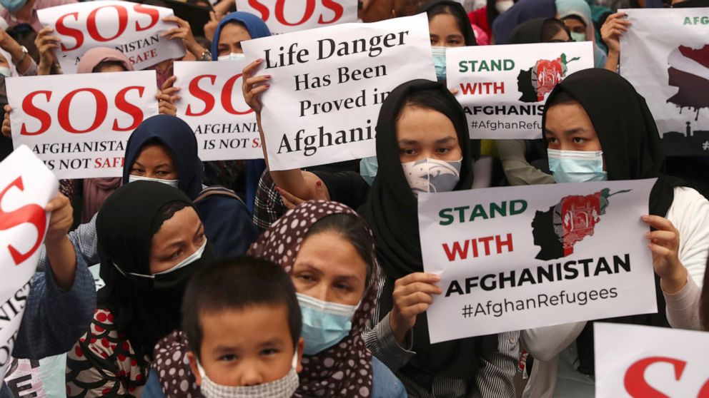 Afghan refugees living in Indonesia hold posters during a rally outside the building that houses UNHCR representative office in Jakarta, Indonesia, Tuesday, Aug. 24, 2021. The protesters, mostly members of the Hazara ethnic minority, held the rally o