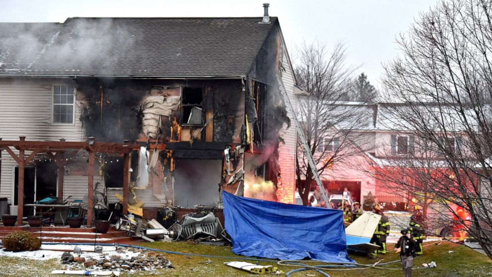 First responders investigate the scene of a plane that crashed into or near a house, setting the house on fire, on Dakota Dr. between Grispen Rd. and Cedar Mill Dr. in Lyon Twp. near the Oakland Southwest Airport, Saturday night, Jan. 2, 2021. (Todd 