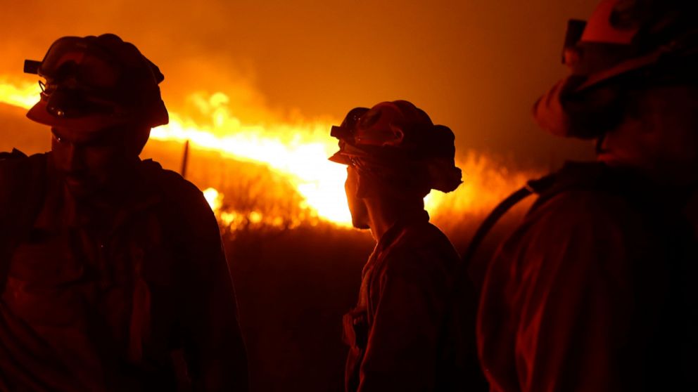 FILE - In this Sept. 12, 2015 file photo, California Department of Corrections and Rehabilitation inmates stand guard as flames from the Butte Fire approach a containment line near San Andreas, Calif. Attorneys representing 14 local governments said 