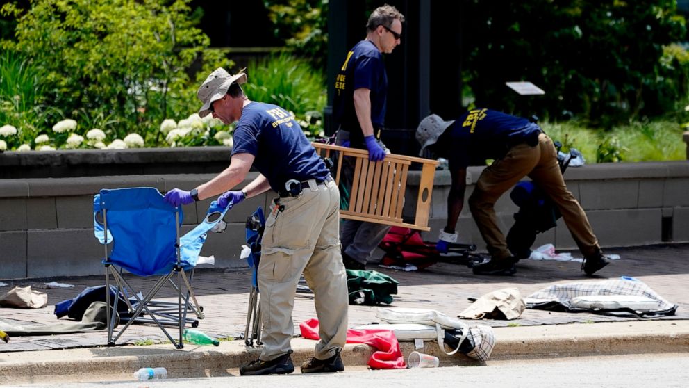 Members of the FBI's evidence response team remove personal belongings one day after a mass shooting in downtown Highland Park, Ill., Tuesday, July 5, 2022. A shooter fired on an Independence Day parade from a rooftop spraying the crowd with gunshots