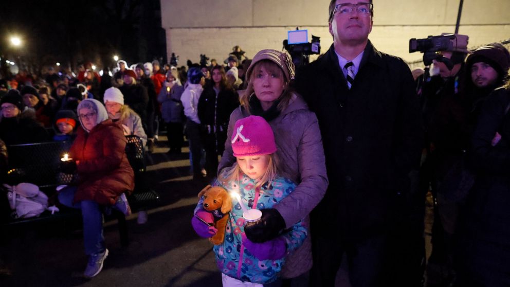 A small child takes part in a candle light vigil in downtown Waukesha, Wis., Monday, Nov. 22, 2021 after an SUV plowed into a Sunday Christmas parade killing multiple people and injuring dozens. (AP Photo/Jeffrey Phelps)