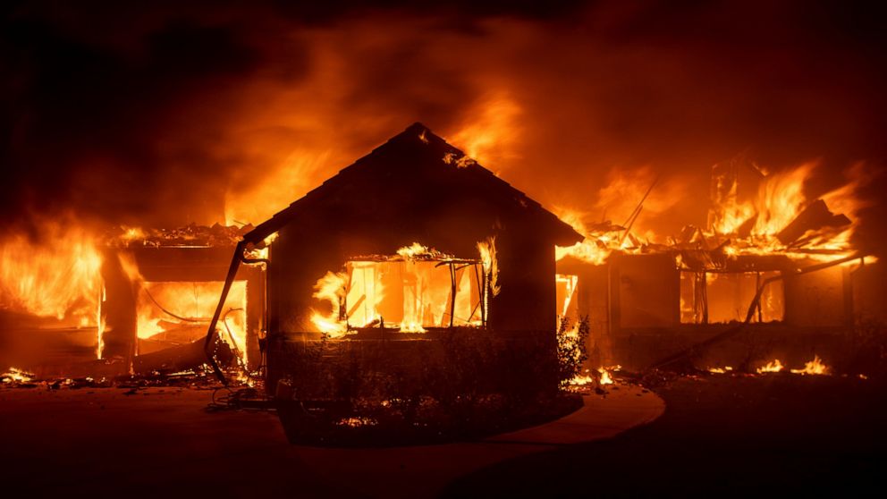 FILE - In this Oct. 31, 2019 file photo flames from the Hillside Fire consume a home in San Bernardino, Calif. President Donald Trump on Sunday, Nov. 3 threatened to cut U.S. funding to California for aid during wildfires that have burned across the 