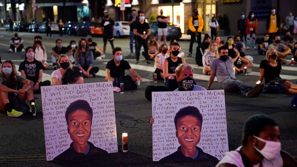 FILE - In this Aug. 24, 2020, file photo, two people hold posters showing images depicting Elijah McClain during a candlelight vigil for McClain outside the Laugh Factory in Los Angeles. Colorado police reform advocates say the recent indictments of 