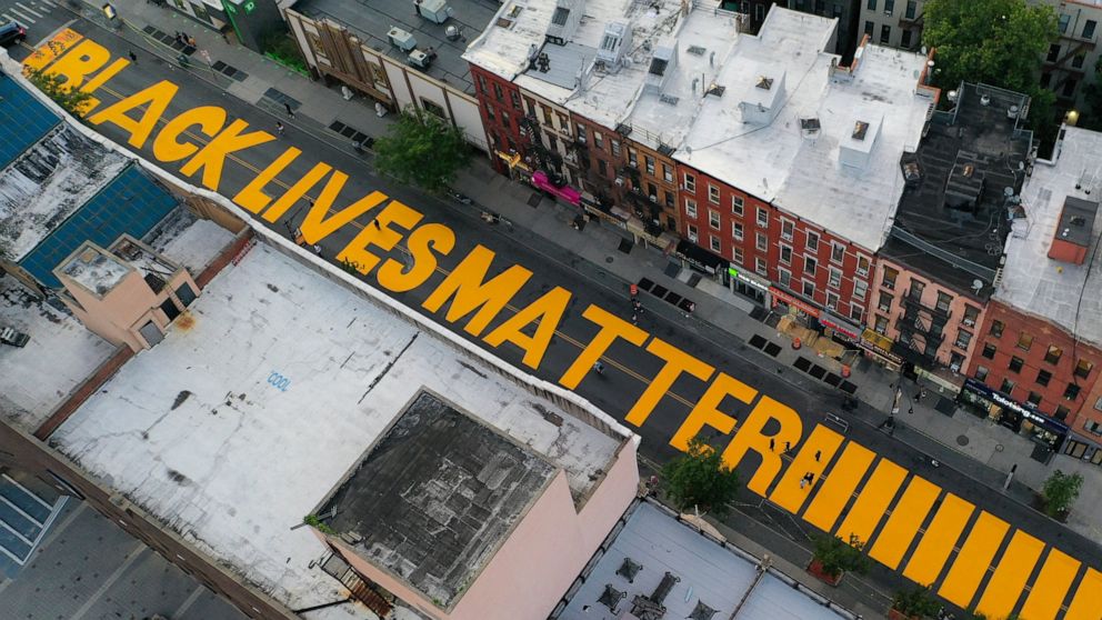 A giant "BLACK LIVES MATTER" sign is painted in orange on Fulton Street, Monday, June 15, 2020, in the Brooklyn borough of New York. (AP Photo/John Minchillo)