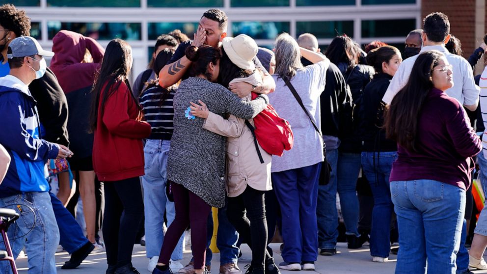 FILE - Edgar James, front center, battles with tears as he hugs his daughter, Mia, front right, and his wife, Olga Aguirre, front left, as they are reunited outside Hinkley High School in Aurora, Colo., on Friday, Nov. 19, 2021. A string of shootings