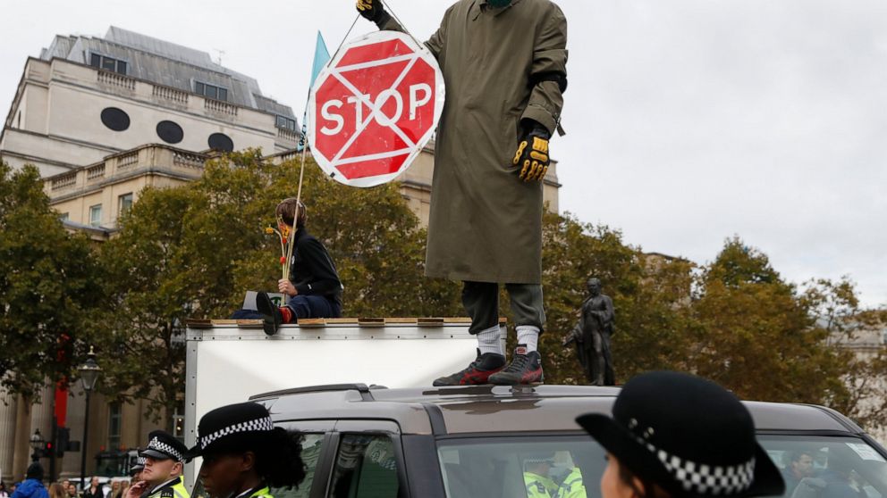 A man wearing a gas mask stand on top of a car as other demonstrators block Trafalgar Square in central London Monday, Oct. 7, 2019. Extinction Rebellion movement blocked major roads in London, Berlin and Amsterdam on Monday at the beginning of what 