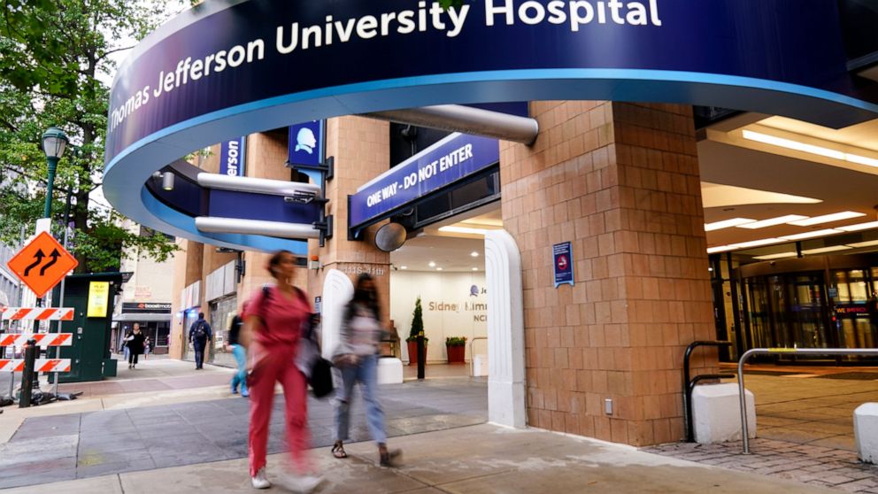 Pedestrians walk past Thomas Jefferson University Hospital in Philadelphia, Monday, Oct. 4, 2021. Police in Philadelphia say a nurse fatally shot his co-worker at a hospital, fled the scene and was shot in a gunfight with police that wounded two offi