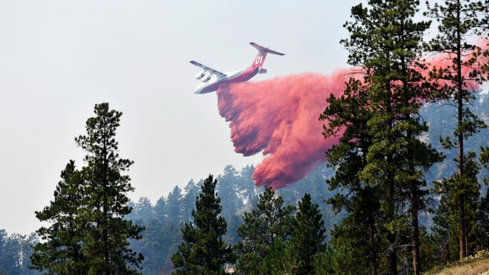 An aircraft drops fire retardant to slow the spread of the Richard Spring fire, east of Lame Deer, Mont., Wednesday, Aug. 11, 2021. The fire spread quickly Wednesday as strong winds pushed the flames across rough, forested terrain. (AP Photo/Matthew 