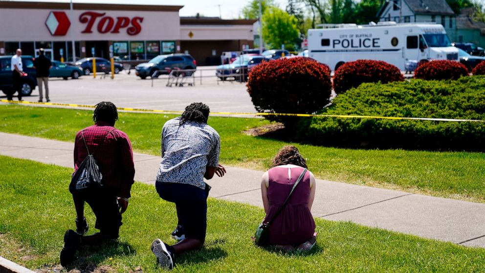 FILE - People pray outside the scene of a shooting where police are responding at a supermarket, in Buffalo, N.Y., May 15, 2022. When police confronted Payton Gendron, the white man suspected of killing 10 Black people at the supermarket, he had an A