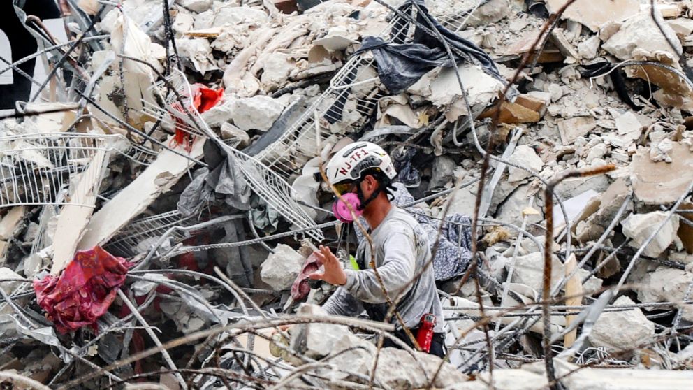 A search and rescue team member moves through the rubble of the Champlain Towers South condo, Wednesday, July 7, 2021. (Al Diaz/Miami Herald via AP)