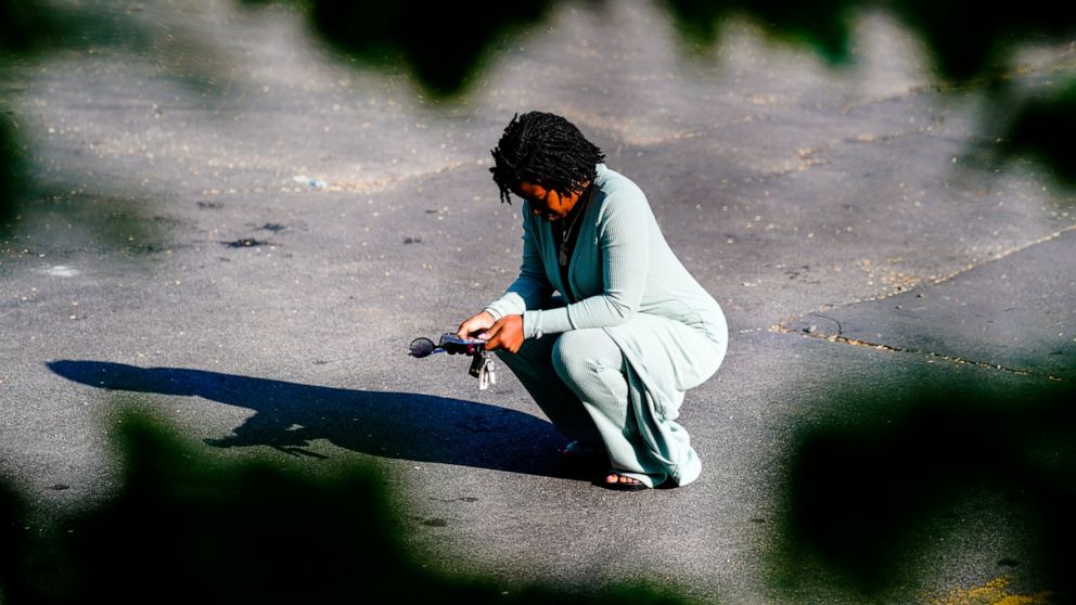 FILE - A woman pauses outside the scene of a shooting at a supermarket, in Buffalo, N.Y., Sunday, May 15, 2022. A white man is accused of shooting 13 people Saturday at the Tops Friendly Market in a predominantly Black neighborhood of Buffalo. Long b