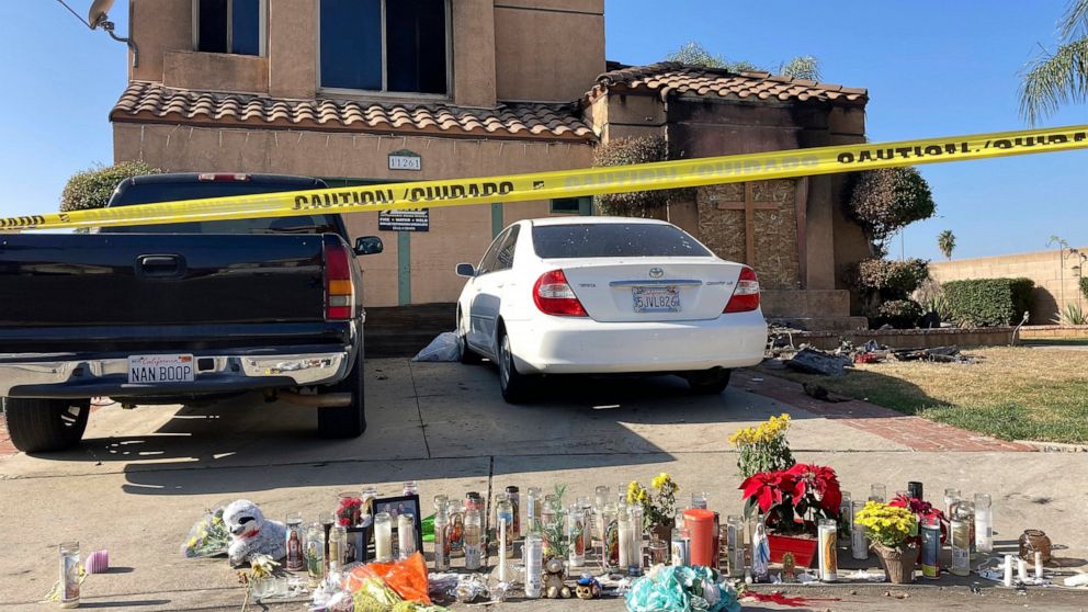 Dozens of candles are laid on the sidewalk, along with bouquets of flowers and stuffed animals outside of a charred home in Riverside, Calif., Wednesday, Nov. 30, 2022. Authorities believe a suspect parked his vehicle in a neighbor's driveway, walked
