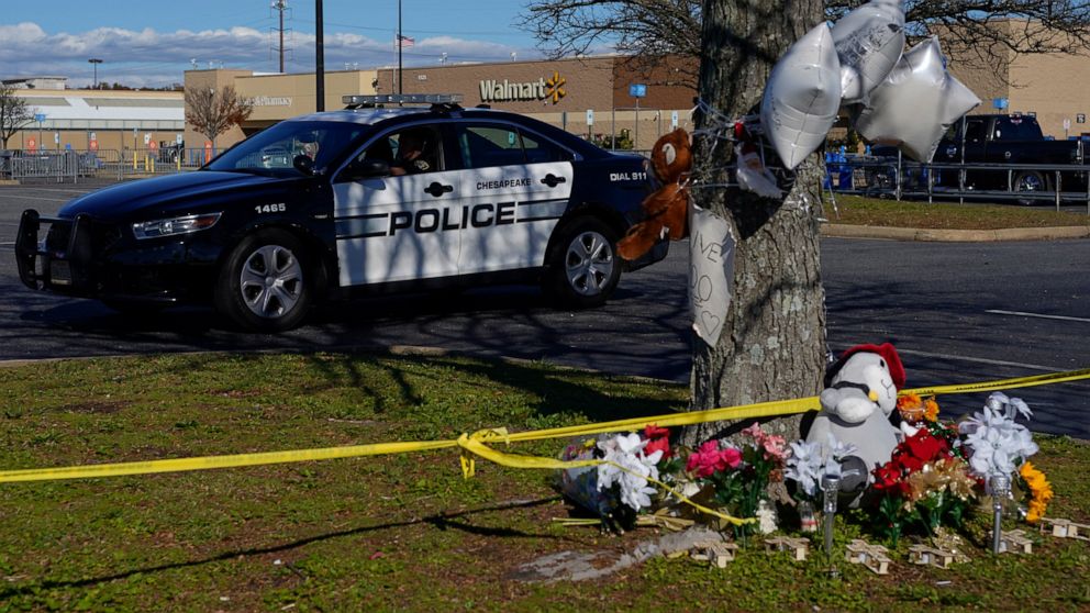 FILE - A police vehicle drives past a makeshift memorial in the parking lot of a Walmart in Chesapeake, Va., Nov. 28, 2022, for the six people killed at the Walmart when a manager opened fire with a handgun before an employee meeting on Nov. 22. The 