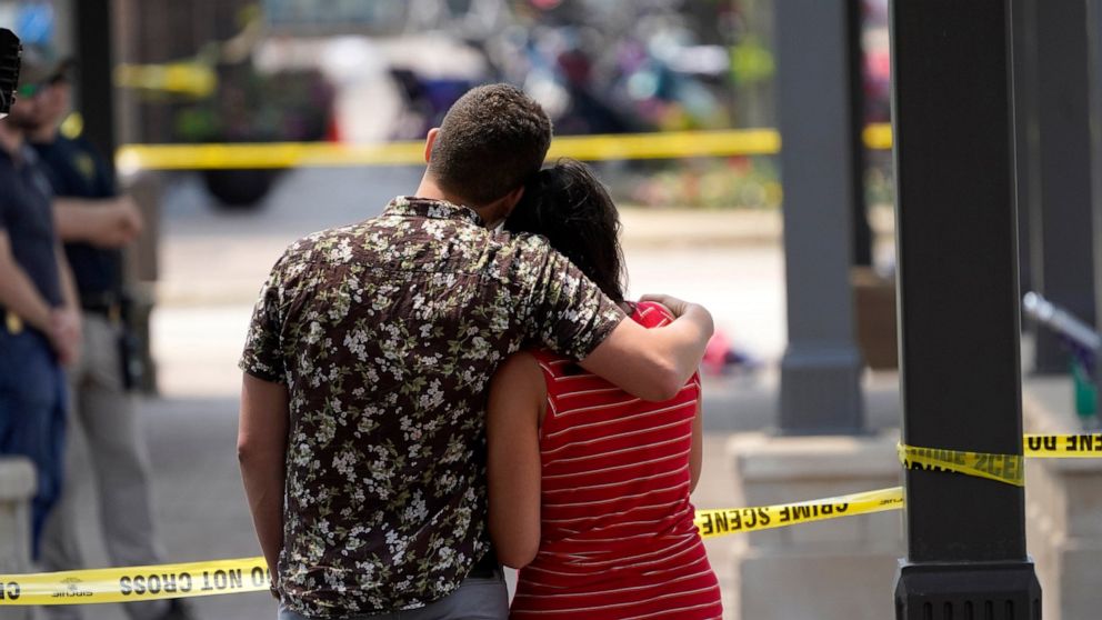 Brooke and Matt Strauss, who were married Sunday, look toward the scene of the mass shooting in downtown Highland Park, Ill., a Chicago suburb, after leaving their wedding bouquets near the scene of Monday's mass shooting, Tuesday, July 5, 2022. (AP 