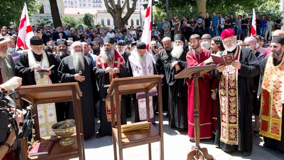 Georgian Orthodox priests, opponents of the march, pray as they block off the capital's main avenue to an LGBT march in Tbilisi, Georgia, Monday, July 5, 2021. A protest against a planned LGBT march in the Georgian capital turned violent on Monday as