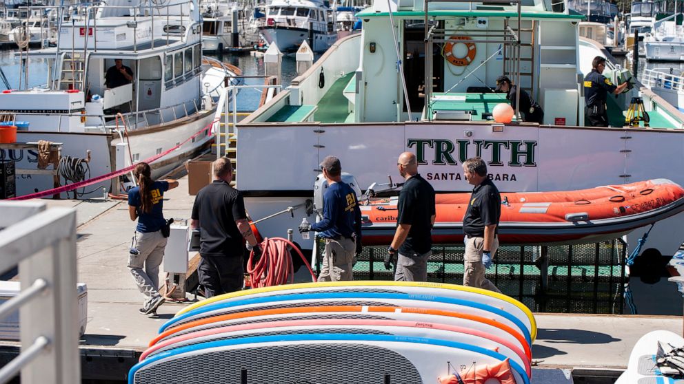 Authorities walk outside the Truth, a Truth Aquatics-owned dive boat, docked in the Santa Barbara Harbor in Santa Barbara, Calif., Sunday, Sept. 8, 2019. Authorities served search warrants Sunday at the Southern California company that owned the scub