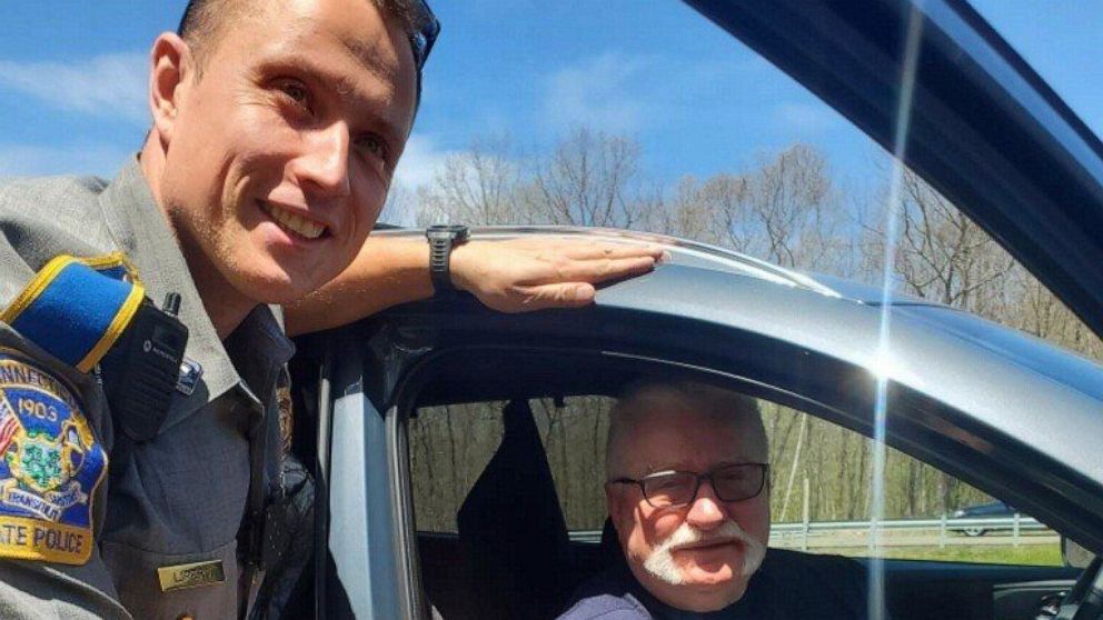 In this photo provided by the Connecticut State Police, Trooper Lukasz Lipert shakes hands with former Polish President Lech Walesa on Interstate 84 in Tolland, Conn., on Wednesday, May 11, 2022. State police said Lipert responded to the call of an S