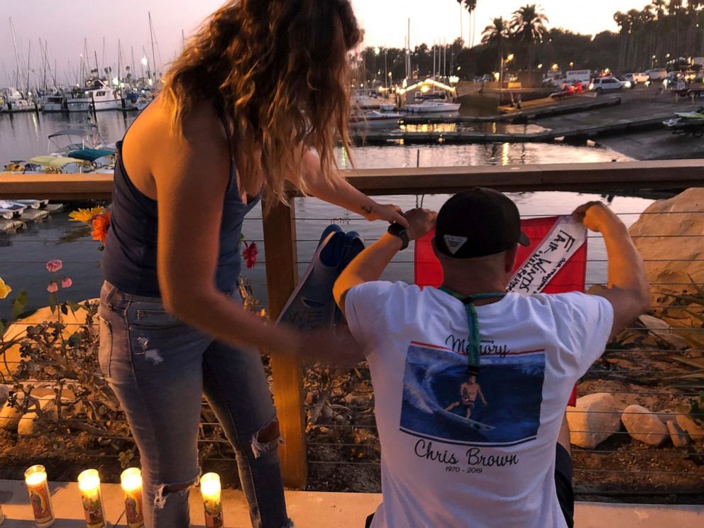 JJ Lambert, 38, and his fiancee, Jenna Marsala, 33, hang up a dive flag in remembrance of the victims of the Conception boat fire at a memorial site on Monday, Sept. 2, 2019, in Santa Barbara, Calif. A fire raged through the boat carrying recreationa