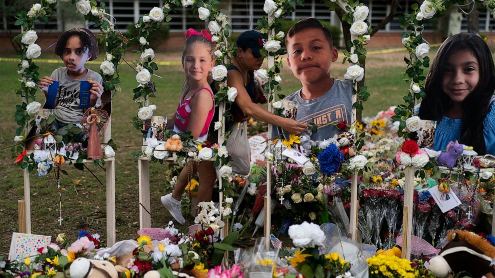 Cat Perez, 39, lays flowers at a memorial at Robb Elementary School in Uvalde, Texas Monday, May 30, 2022, to honor the victims killed in last week's school shooting. Photographs of the victims, from left, show Layla Salazar, McKenna Lee Elrod, Jayce