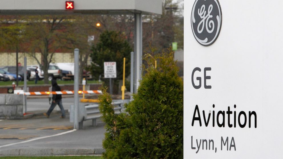 In this April 19 2011 file photo the General Electric logo is seen on a sign at the entrance to the aviation manufacturing plant in Lynn, Mass. The largest union representing workers for General Electric Co. says it's reached an agreement with the co