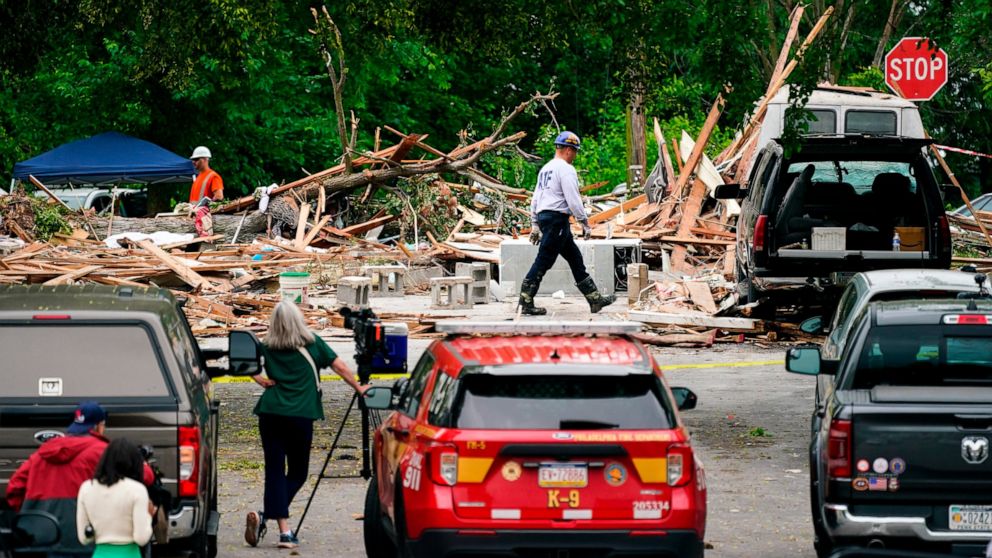 An investigator, center top, moves through the scene of a deadly explosion in a residential neighborhood in Pottstown, Pa., Friday, May 27, 2022. A house exploded northwest of Philadelphia, killing several people and leaving a few others injured, aut