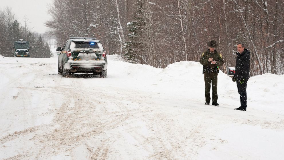 FILE — A Vermont State Trooper, center, speaks to a homeowner Thursday, Jan. 8, 2018, near an area on Peacham Road, in Barnet, Vt., where the body of Gregory Davis was found. Two of the men charged in the murder for hire case that led to the 2018 kil