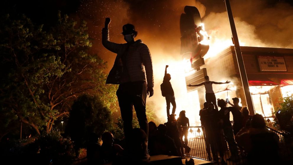 FILE - In this May 29, 2020, file photo, protesters gather in front of a burning fast food restaurant in Minneapolis. An external review of Minnesota's response to the civil unrest following the May 2020 killing of George Floyd found several weakness