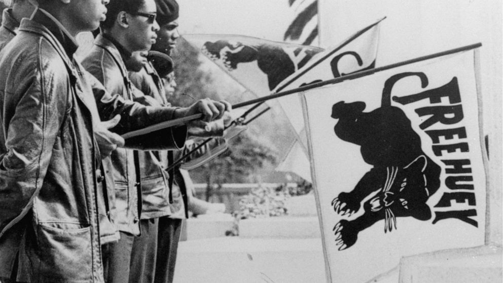 FILE - In this August 1968 file photo, a group of Black Panthers hold flags outside the Alameda County Court House, Oakland, Calif., during the Huey Newton trial. Newton was convicted of voluntary manslaughter in the shooting death of an Oakland poli