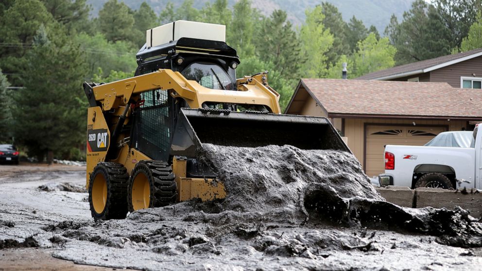 A bobcat moves a wet slurry of ash, mud and forest debris into a pile to be removed after the muck was left behind from flooding caused by a monsoon rain event over the 2019 Museum Fire burn area in Flagstaff, Ariz., on Wednesday, July 14, 2021. The 