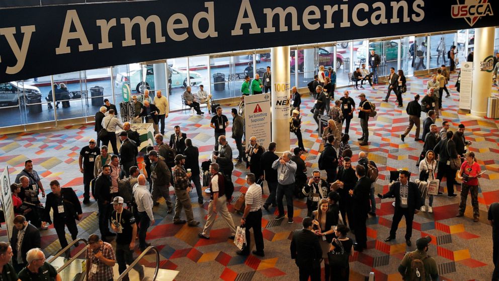 FILE - In this Wednesday, Jan. 24, 2018, file photo, people walk through the hall outside of the SHOT Show gun show in Las Vegas. The gun industry is gathering for its annual conference, in January 2020, amid a host of uncertainty: slumping gun sales