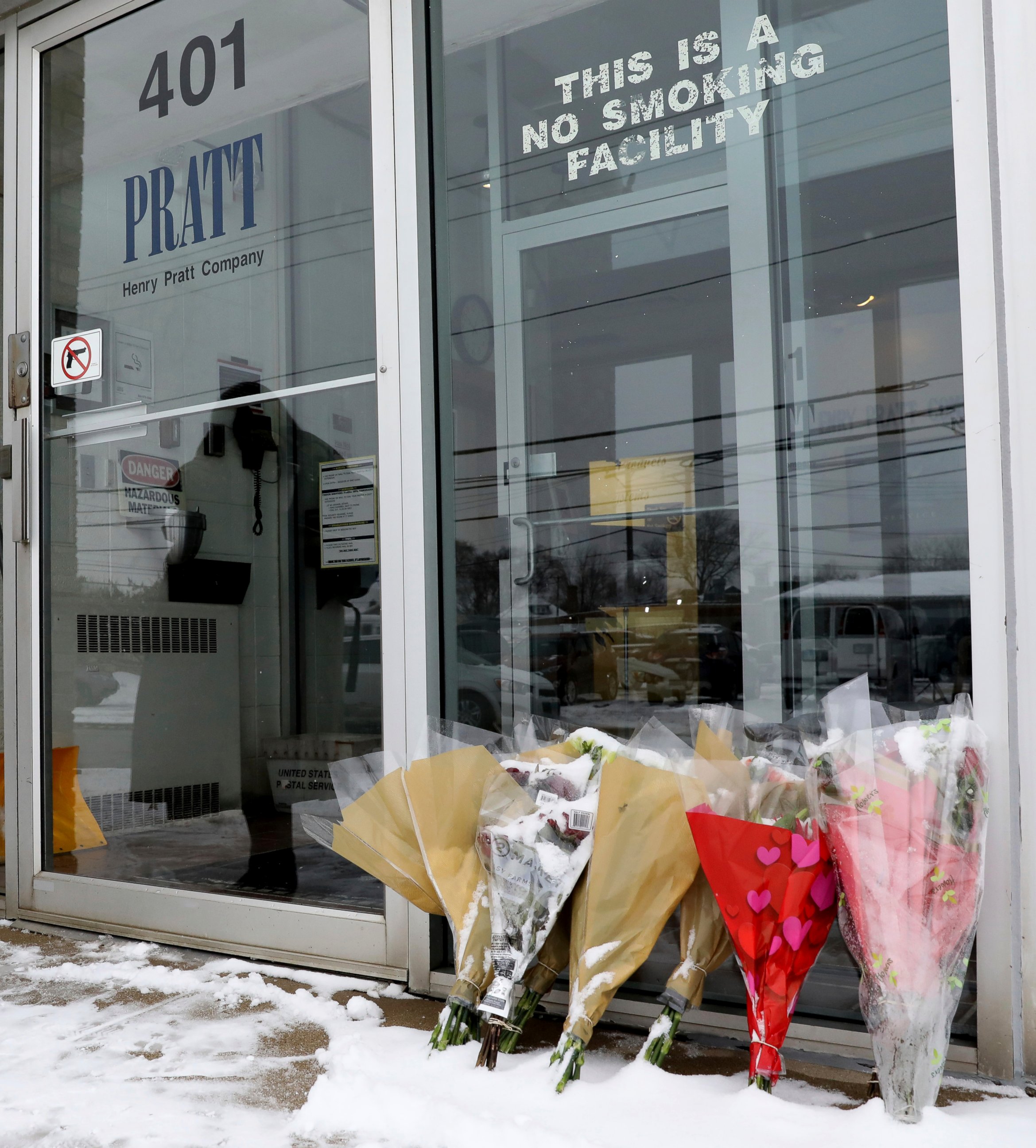 FILE - In this Feb. 17, 2019 file photo bouquets of flowers are placed for victims in front of the warehouse of Henry Pratt Co., in Aurora, Ill. A report on the February shooting at the suburban Chicago manufacturing plant found that the man who kill