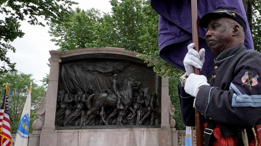 Civil War reenactor Larry Harris, of Philadelphia, right, marches past the Robert Gould Shaw and the 54th Massachusetts Regiment Memorial, left, that commemorates the famed Civil War unit made up of Black soldiers, during re-dedication ceremonies of 